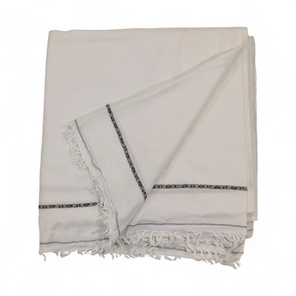 A pure pashmina shawl in crisp white, folded and draped, featuring subtle black and white patterned border details and fringed edges, displayed on a white background.
